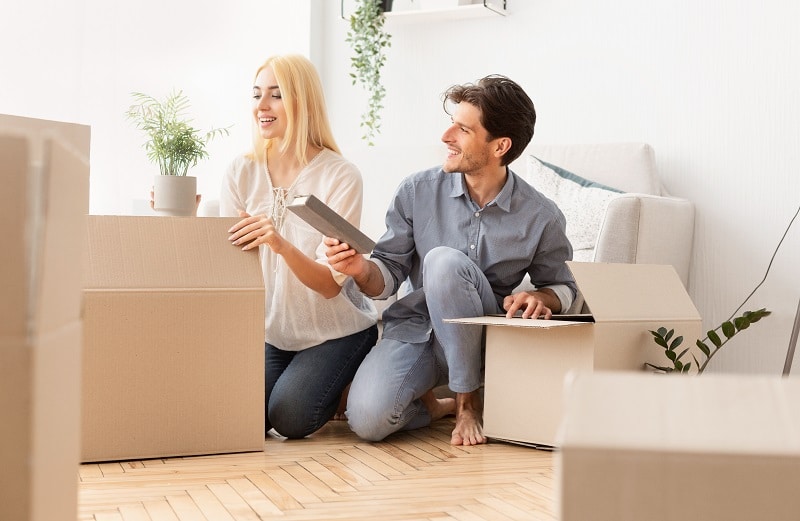 Young Spouses Unpacking Moving Boxes In New House After Relocation