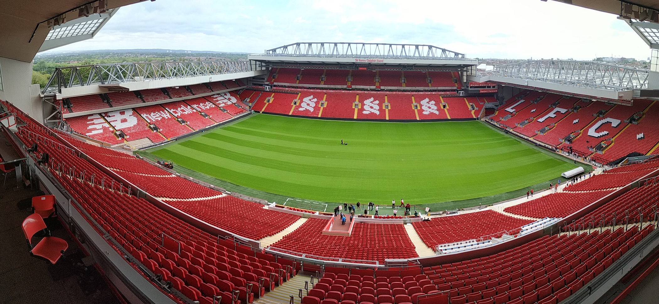  A panoramic view of the inside of Anfield, the home stadium of Liverpool Football Club, showing the empty stands and the green pitch.