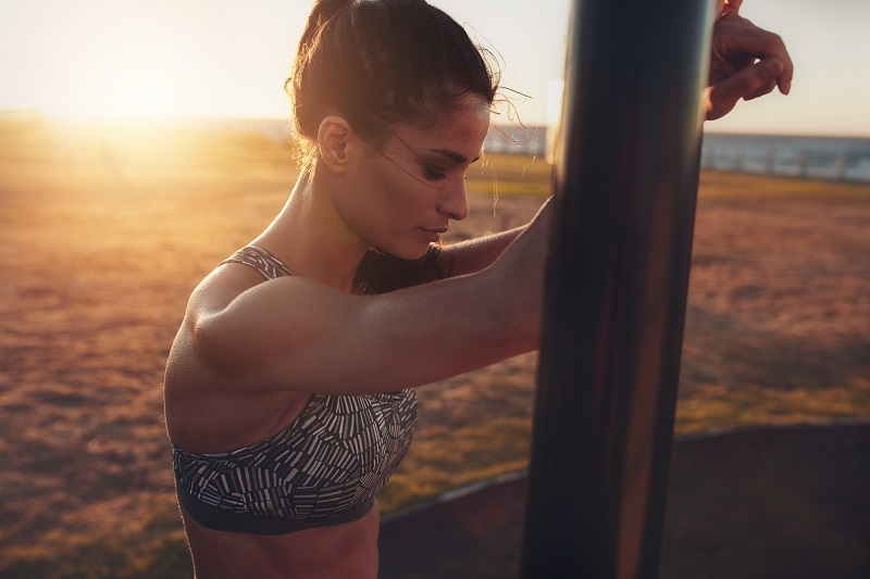 Sportswoman leaning to exercise equipment on the beach