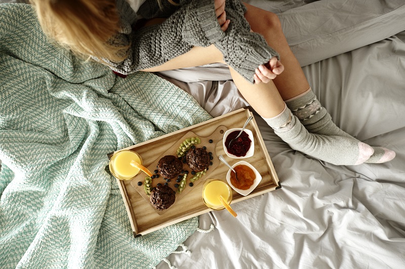 Unrecognizable woman and breakfast on bed