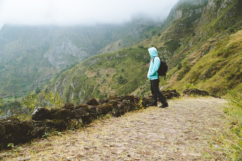 Active vacation tourism. Man enjoying impressive mountainscape. Arid canyon valley extend far below. Santo Antao, Cabo Verde