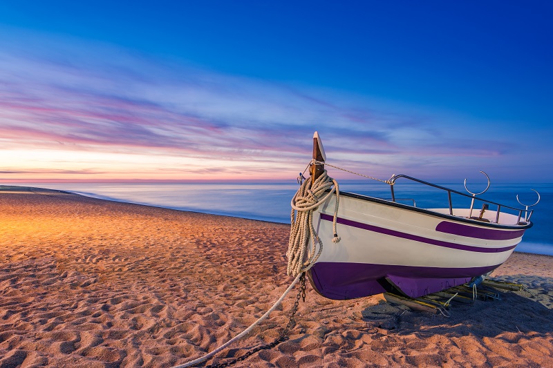 Old wooden fishing boat on beach at sunrise