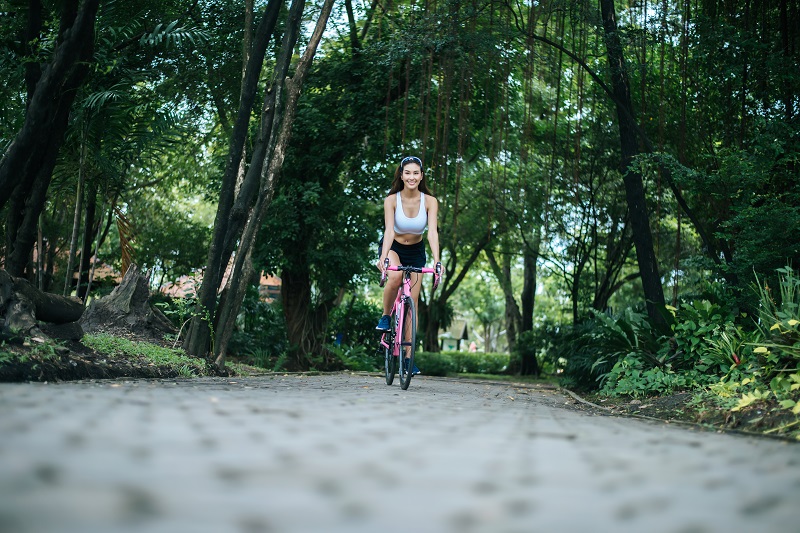 Woman riding a road bike in the park. Portrait of young beautifu