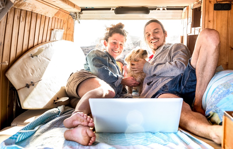 Digital nomad couple with cute dog using laptop on retro mini va