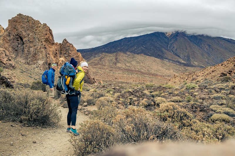 Family hiking with baby boy travelling in backpack