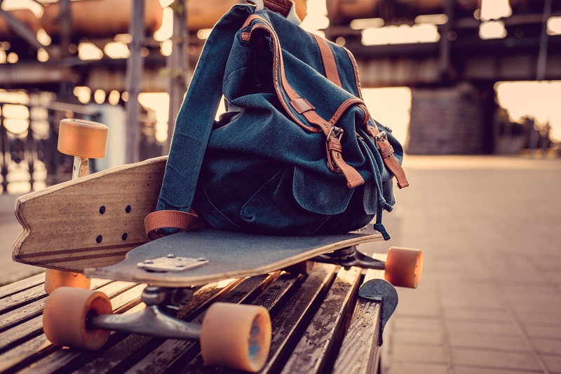 Longboard and backpack on a bench.