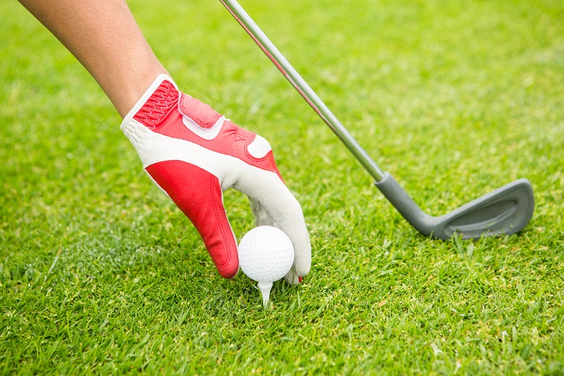 Golfer placing golf ball on tee at the golf course