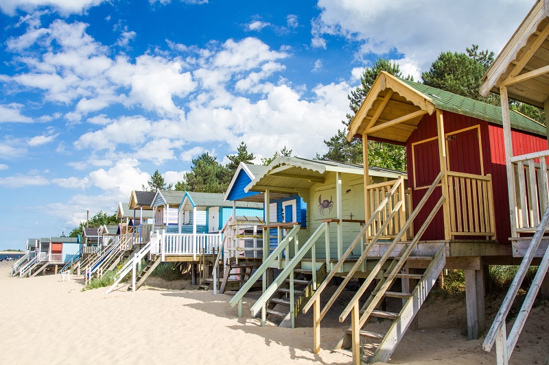 row-of-colourful-beach-huts-on-a-sandy-beach-in-a
