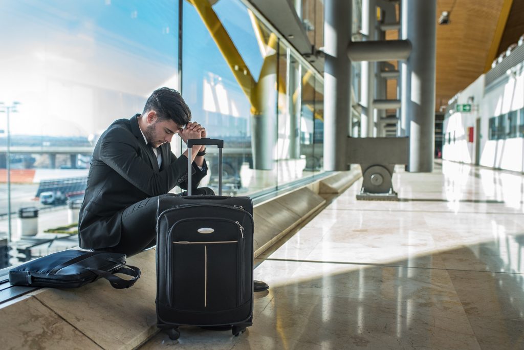 young businessman angry at the airport waiting his delayed flight with luggage