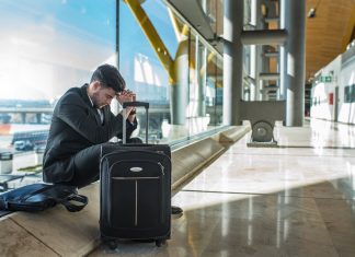 young businessman angry at the airport waiting his delayed flight with luggage
