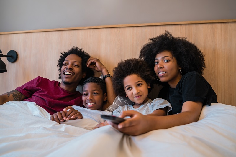 Family watching a movie on bed at home.
