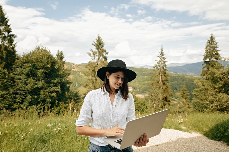 Hipster girl with laptop sitting on wooden porch