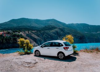 Vacation travel with car concept. Rental hired car in front of amazing bay with turquoise water. Discover Mediterranean Islands. Summer time holiday trip