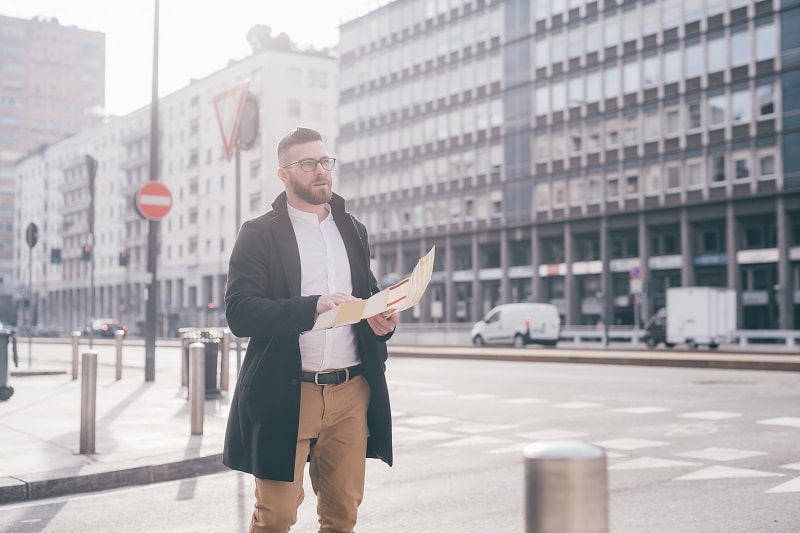 Young bearded man business traveller sightseeing reading map pla