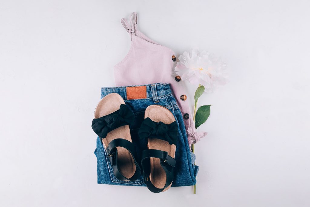 Summer fashion outfit - top, denim shorts, black sandals. Female travel vacation clothes. Flat lay