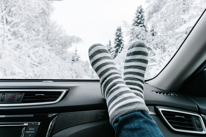 Woman feet in warm socks on car dashboard. Winter time, travel c