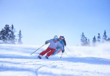 row-of-male-and-female-skiers-skiing-down-snow-covered