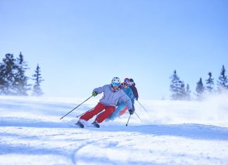 row-of-male-and-female-skiers-skiing-down-snow-covered