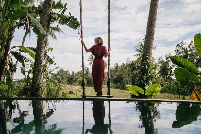 Photo from back of slim woman in long dress looking at rainy sky. Outdoor shot of shapely female mo