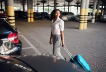 Young woman with suitcase in car parking