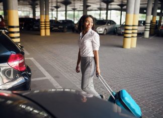 Young woman with suitcase in car parking