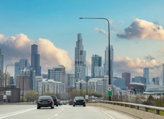 Chicago Illinois, USA. Cars on the road driving to Chicago city, high rise buildings and cloudy sky background