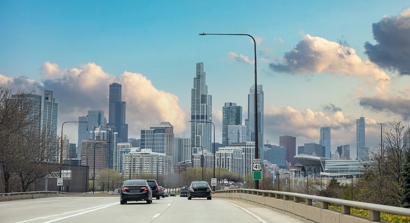 Chicago Illinois, USA. Cars on the road driving to Chicago city, high rise buildings and cloudy sky background