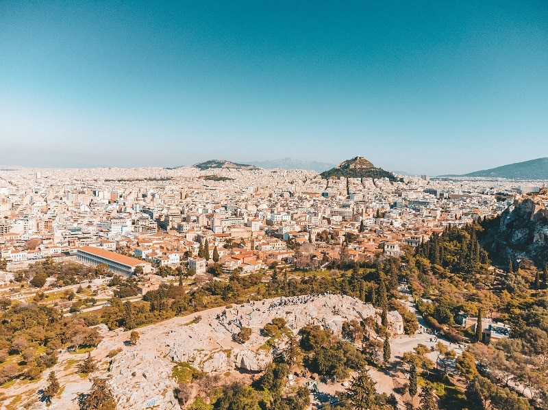 the city of athens from above with hills and trees in the foreground