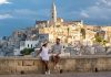 A couple enjoys the stunning sunset view over Matera ancient stone architecture in Puglia, Italy