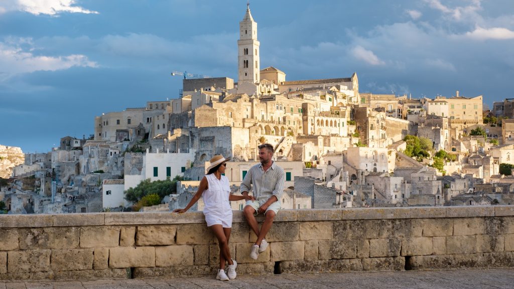 A couple enjoys the stunning sunset view over Matera ancient stone architecture in Puglia, Italy