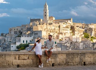 A couple enjoys the stunning sunset view over Matera ancient stone architecture in Puglia, Italy