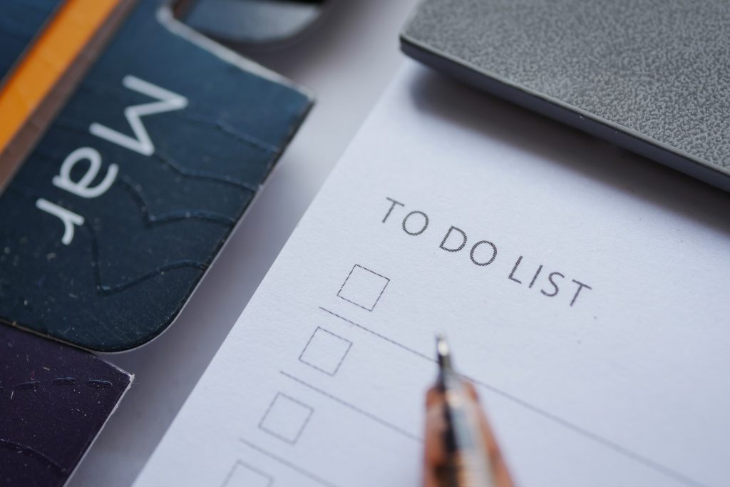 To do list in notebook with office suppliers on desk